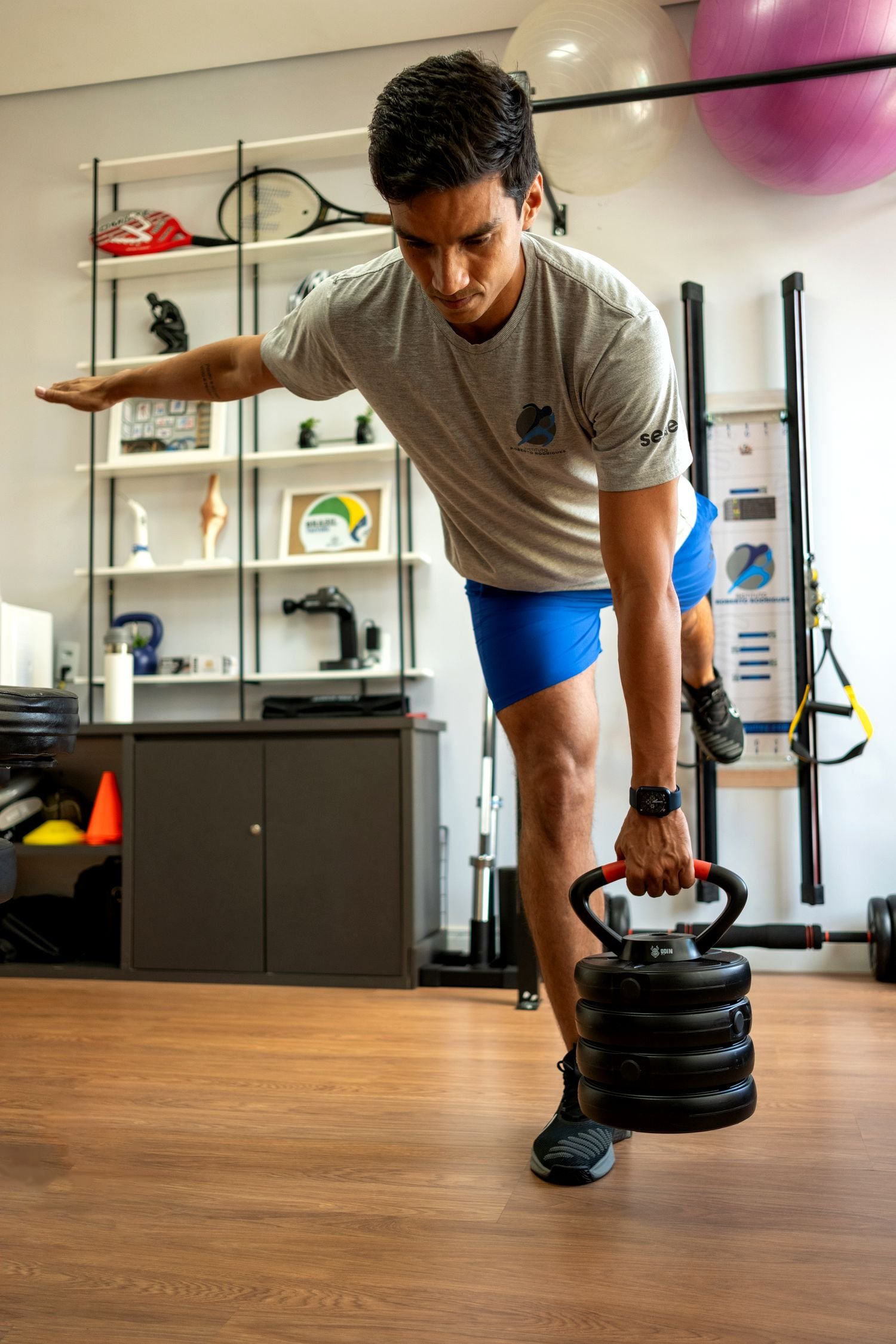 Paciente em treino de força unilateral com kettlebell na sala de treino do Instituto Roberto Rodrigues